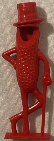 Vintage red plastic Mr. Peanut figural whistle with top hat, shown standing against beige fabric background