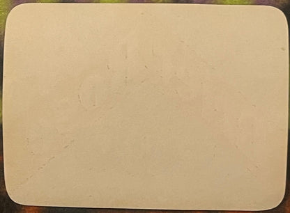 Blank cream-colored rectangular label with rounded corners on green fabric background, showing age spots and slight wear