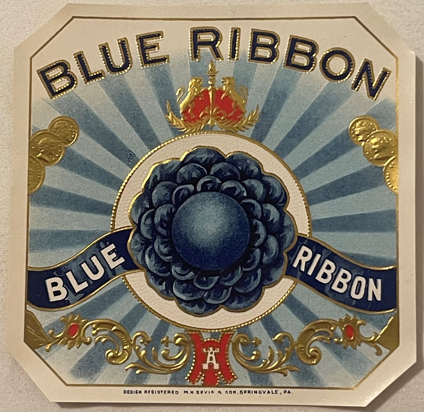 Antique gold-embossed cigar box label featuring "Blue Ribbon" text, central blue berry cluster, crown, and decorative scrollw