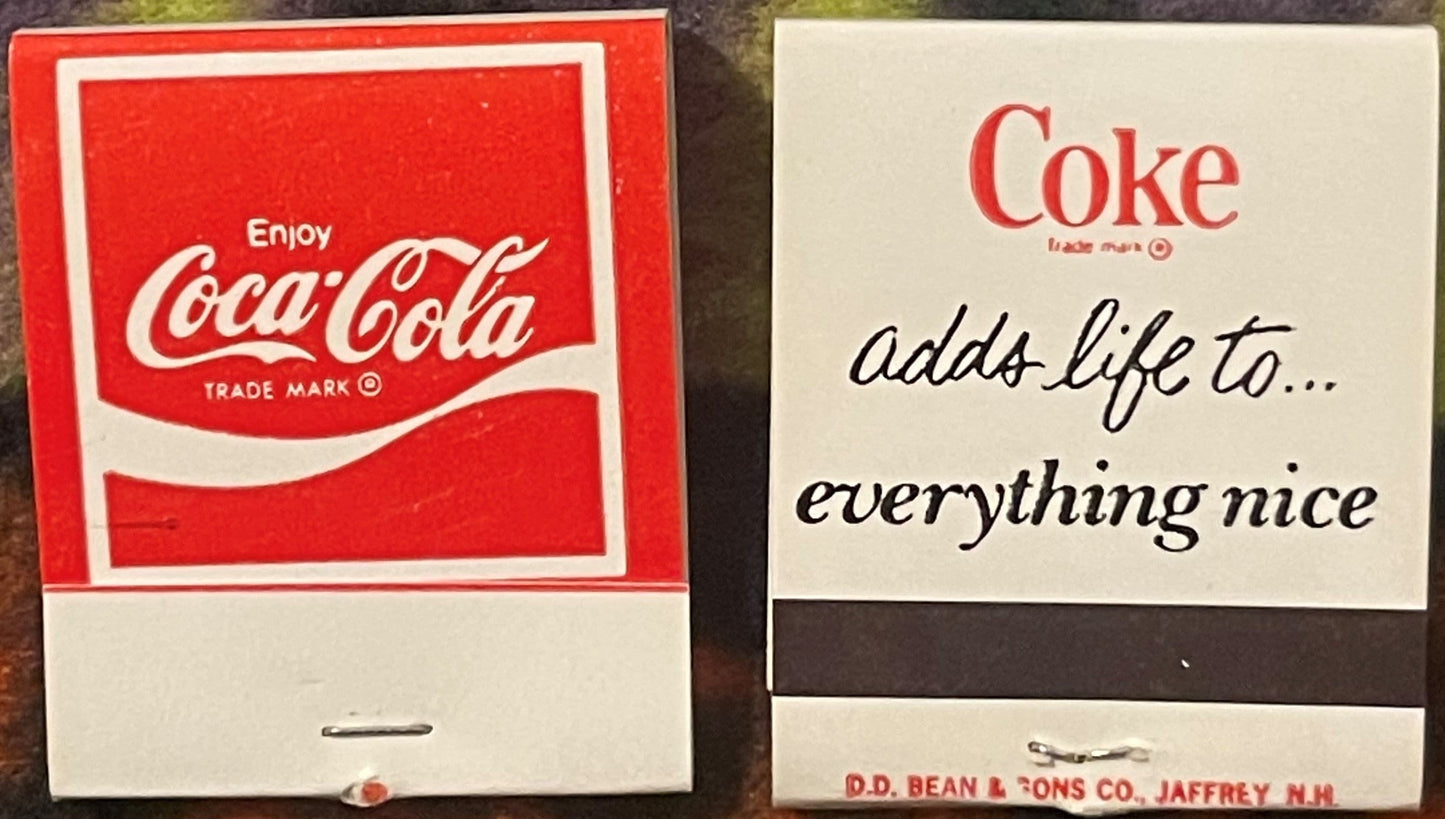 Two vintage Coca-Cola matchbooks displayed side by side: left shows classic red "Enjoy Coca-Cola" design; right displays "Cok