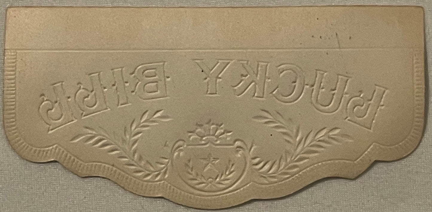 Embossed tan cardboard cigar box lid detail showing "LUCKY FOUR LEAF" text with decorative laurel branches and ornamental cre
