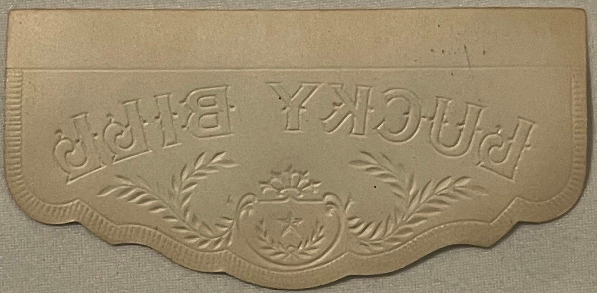 Embossed tan cardboard cigar box lid detail showing "LUCKY FOUR LEAF" text with decorative laurel branches and ornamental cre