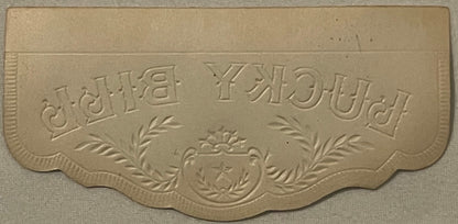 Embossed tan cardboard cigar box lid detail showing "LUCKY FOUR LEAF" text with decorative laurel branches and ornamental cre