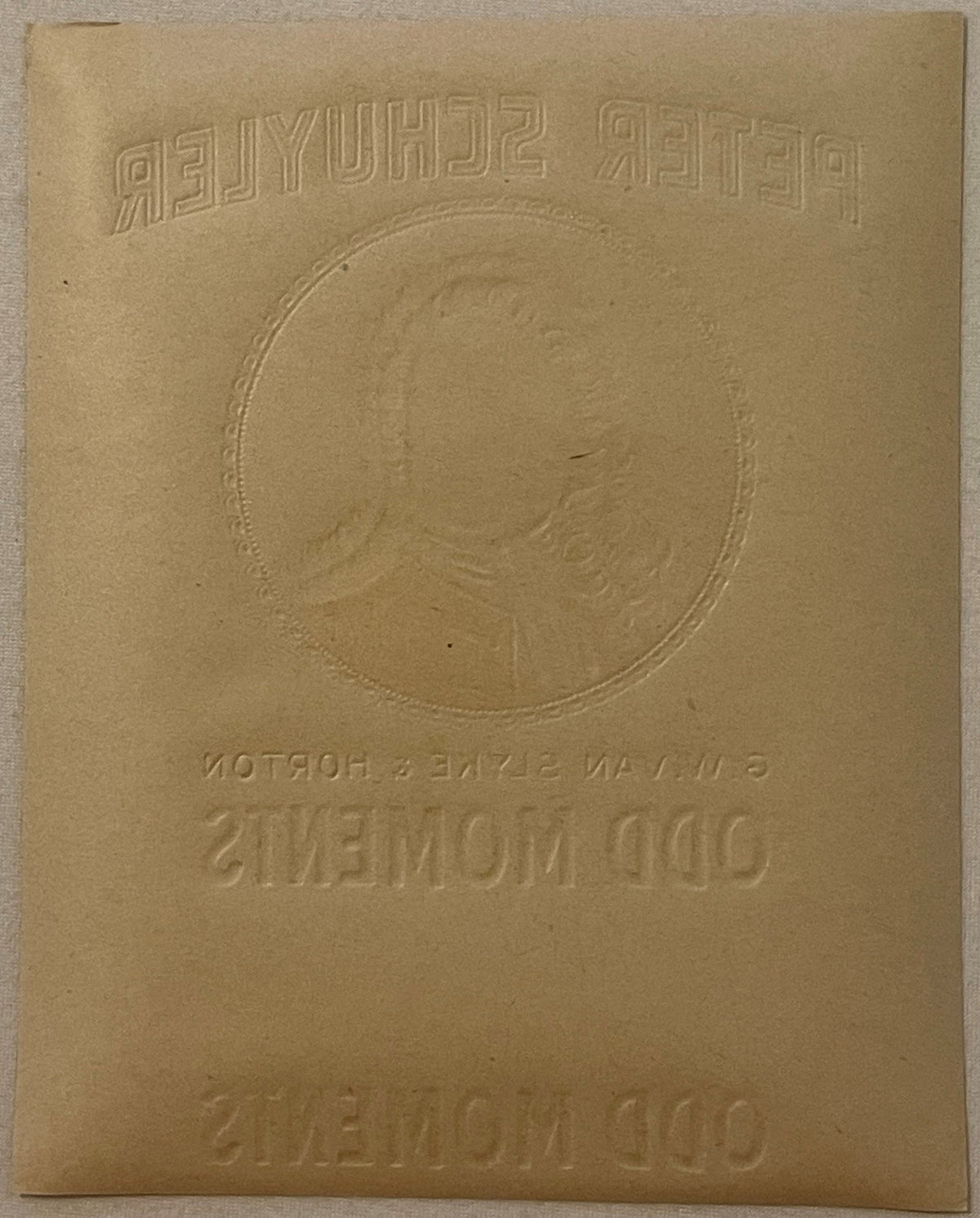 Embossed tan cardboard cigar box label with portrait medallion and reversed text, viewed flat against white surface