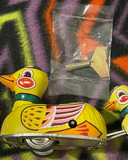 The mother duck with the original wind-up key still sealed in its clear poly bag, and a duckling at the right.
