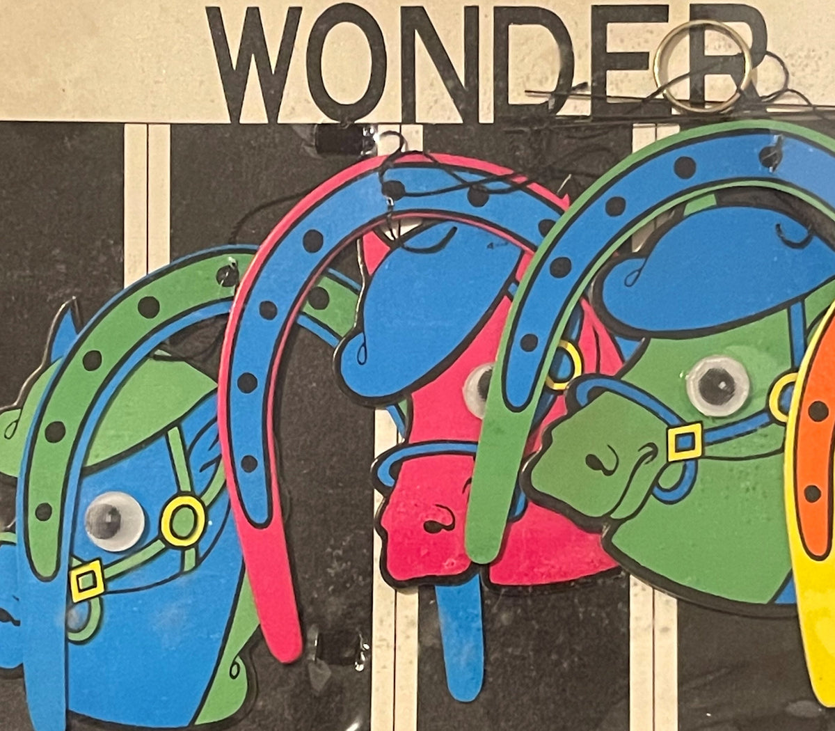 Colorful vintage carousel horse artwork with "WONDER" text at top, featuring blue, green, pink, and yellow painted horses