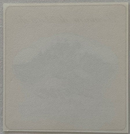 Blank cream-colored square label or paper against gray background, appears unused or back side of vintage spirit label