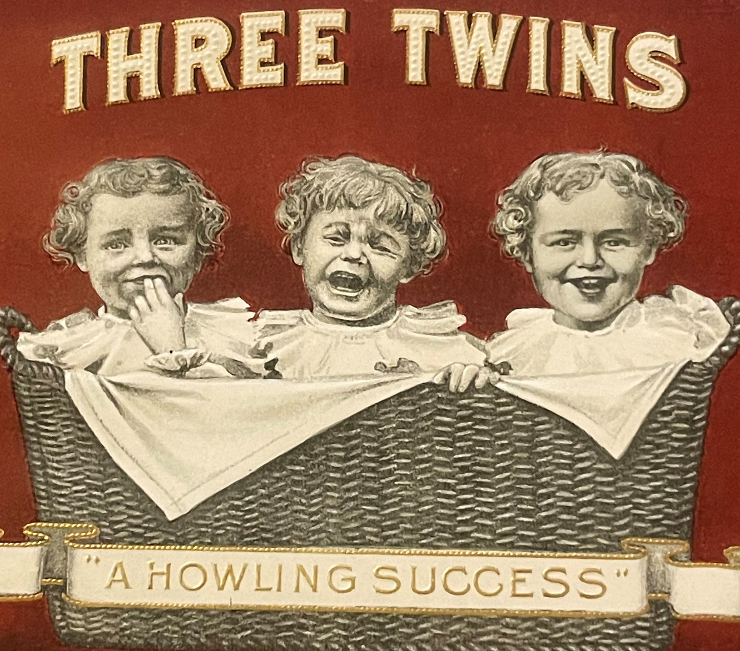 Antique cigar box label featuring three baby faces in a wicker basket with "THREE TWINS" text and "A HOWLING SUCCESS" banner 