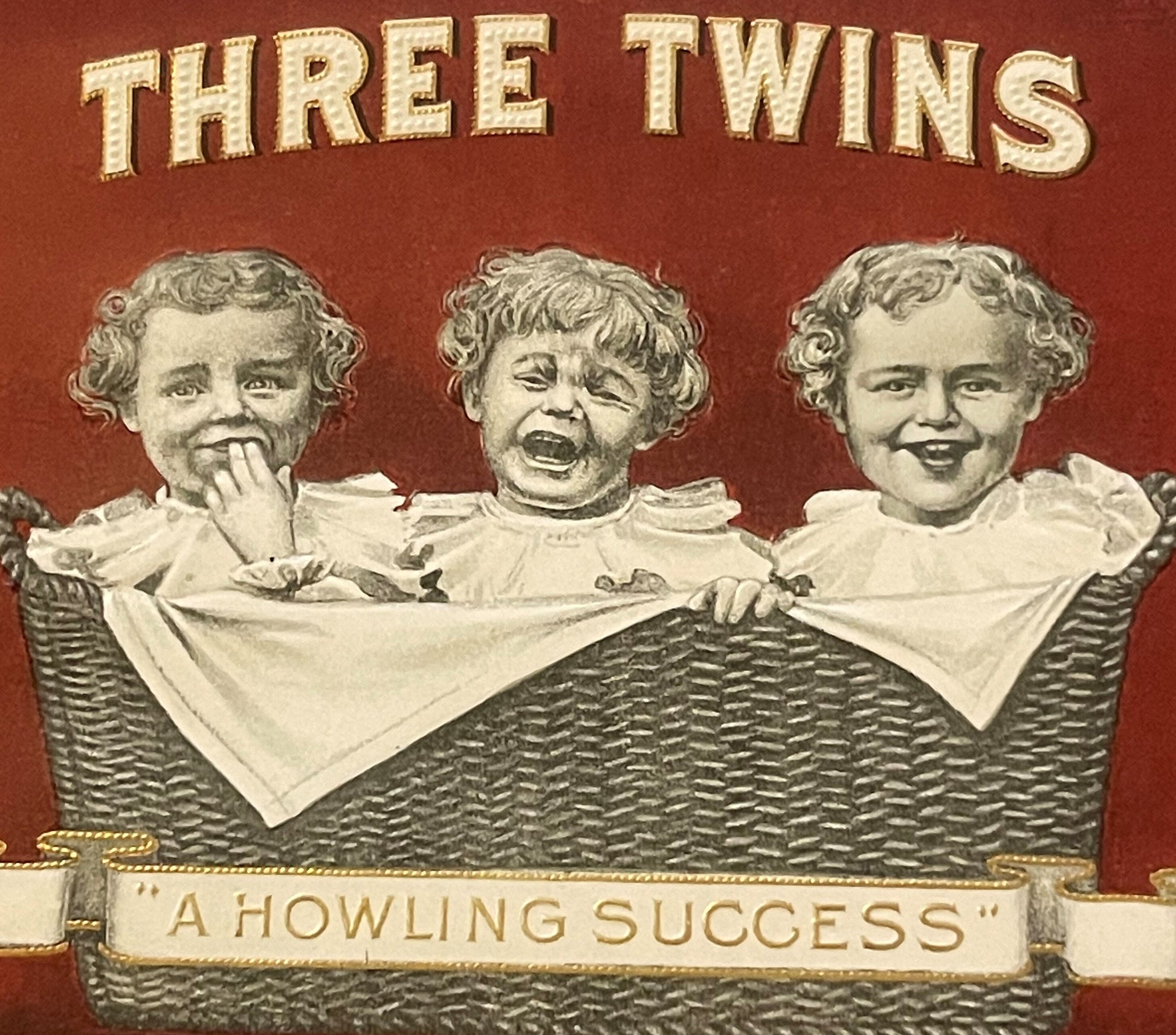 Antique cigar box label featuring three baby faces in a wicker basket with "THREE TWINS" text and "A HOWLING SUCCESS" banner 