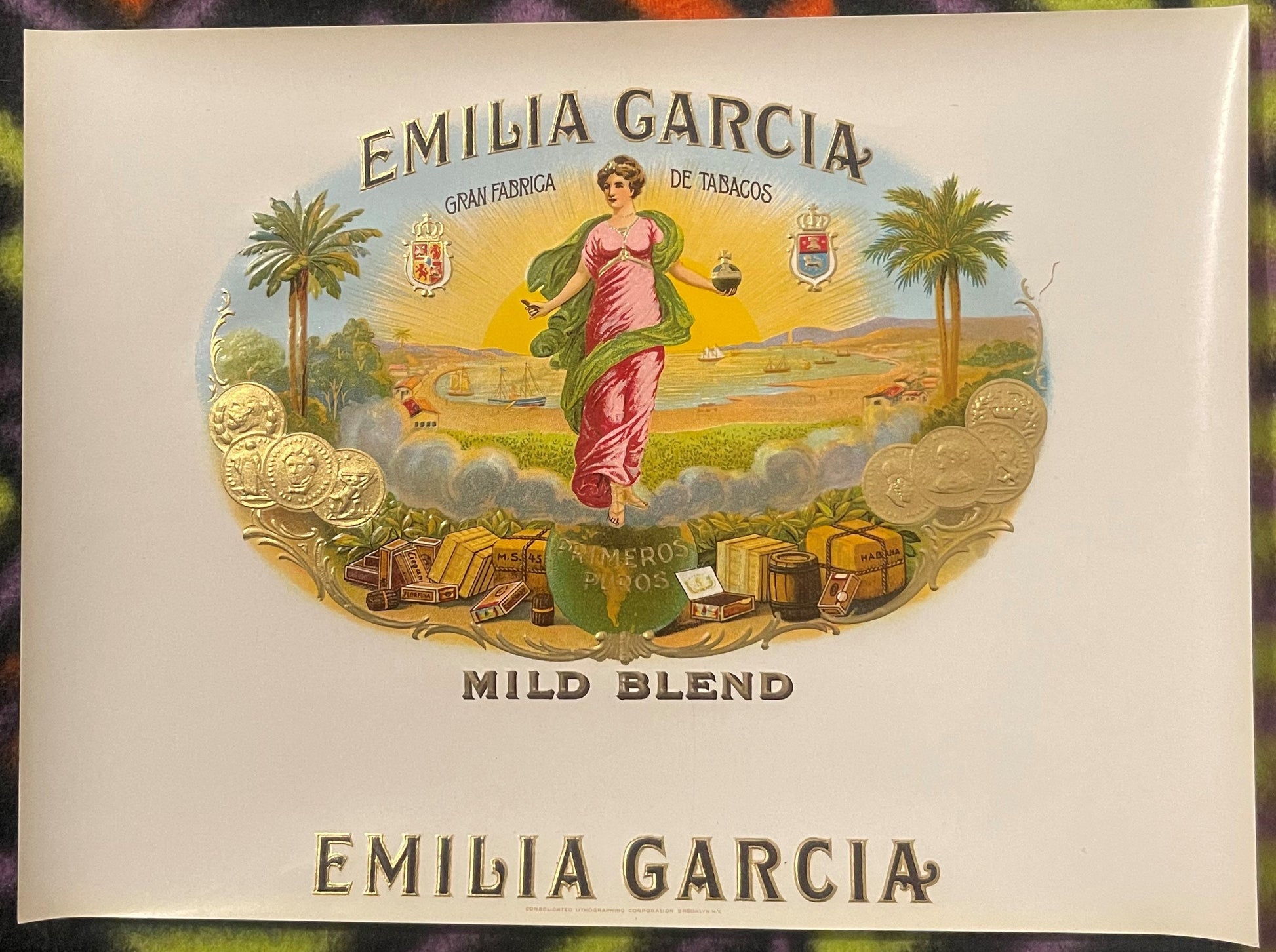 Antique Emilia Garcia cigar box label with embossed gold design featuring a woman in pink robes, palm trees, coins, and "Mild