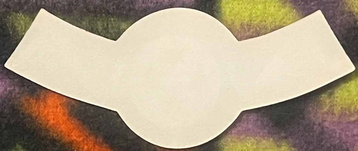 Blank cream-colored wine neck label with scalloped edges displayed against a textured background with purple, green, and oran