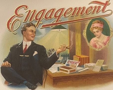 Vintage cigar label with embossed gold lettering "Engagement" showing a man in suit at desk and woman's portrait in circular 