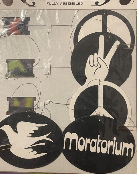 Vintage peace mobile assembly instructions showing black silhouettes of dove, peace hand gesture, and headphones