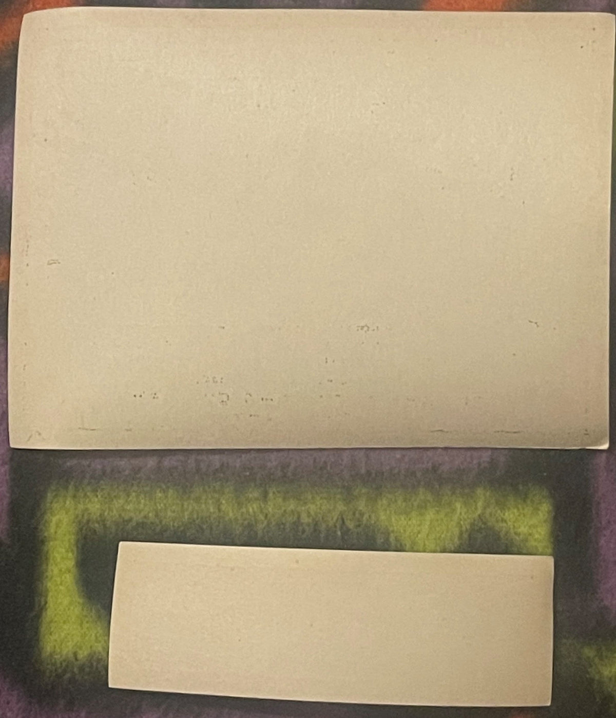Two blank cream-colored vintage ginger ale labels displayed on a green textured fabric background for scale