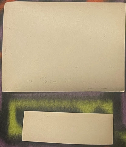 Two blank cream-colored vintage ginger ale labels displayed on a green textured fabric background for scale