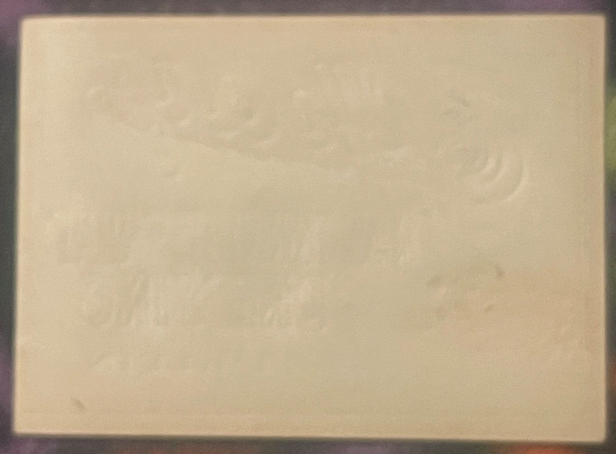 Cream-colored vintage label with faint embossed decorative pattern, photographed flat against dark border