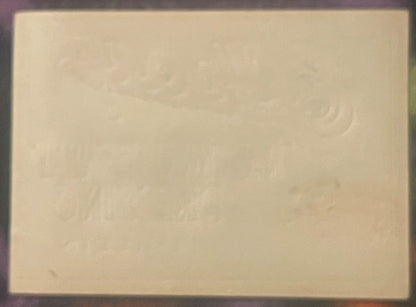 Cream-colored vintage label with faint embossed decorative pattern, photographed flat against dark border