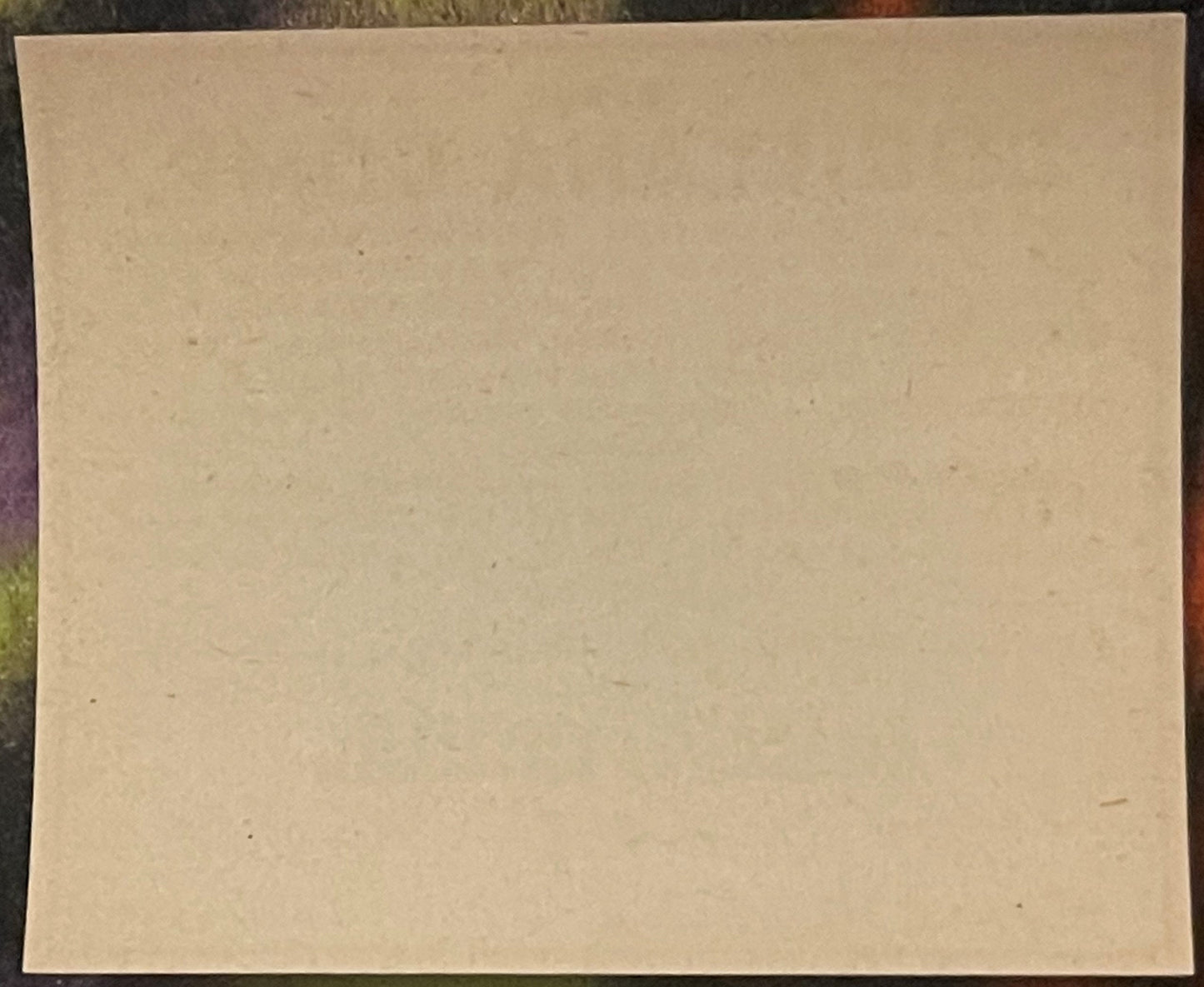Blank cream-colored vintage pharmacy label on dark patterned surface, showing age spots and natural discoloration