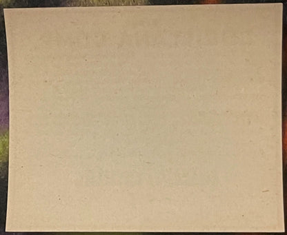 Blank cream-colored vintage pharmacy label on dark patterned surface, showing age spots and natural discoloration