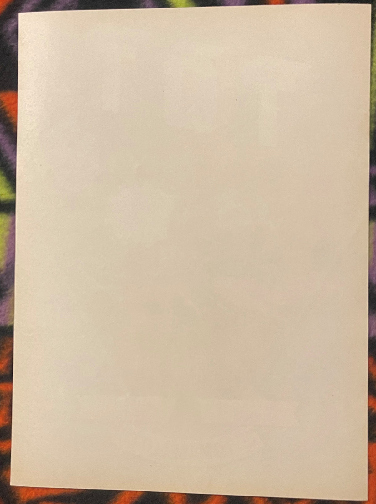Blank cream-colored vintage crate label on colorful patterned background for scale