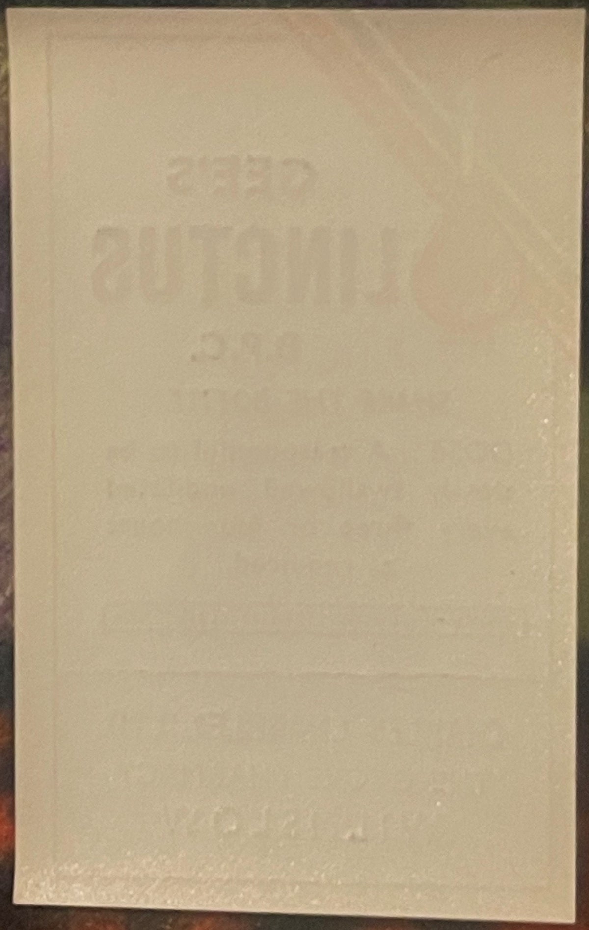 Faded cream-colored vintage medicine label with embossed text, photographed straight-on against dark background