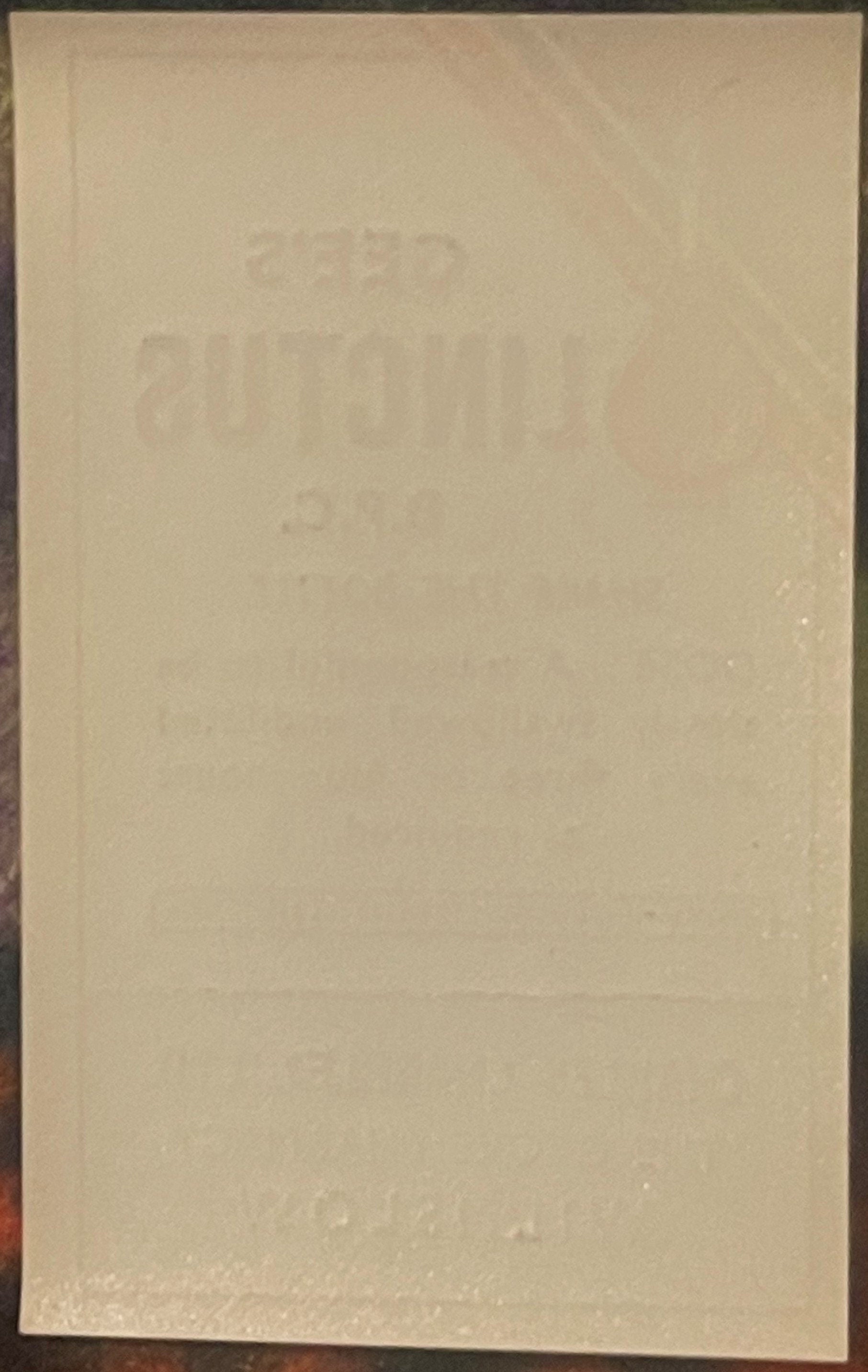Faded cream-colored vintage medicine label with embossed text, photographed straight-on against dark background
