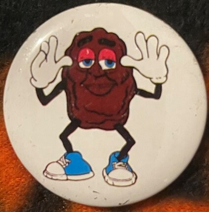 Vintage California Raisins pinback button featuring a smiling red raisin character with white gloves, blue shoes, and pink ey
