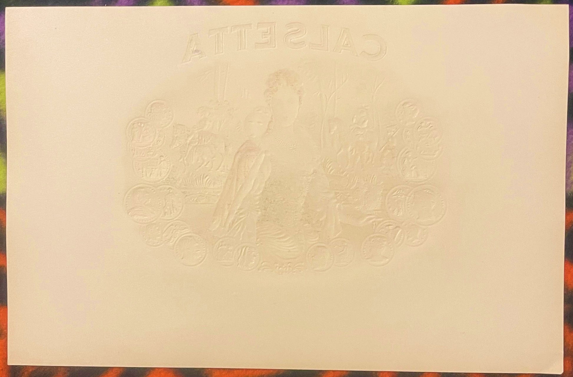 Cream-colored embossed cigar label with "Calsetta" text at top and ornate Victorian royal coat of arms design in center relie