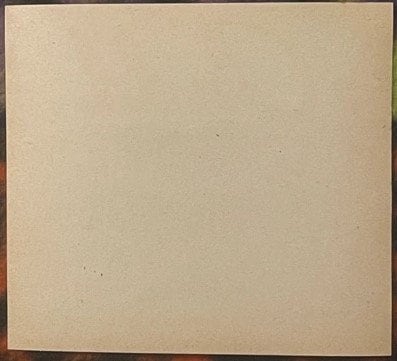 Blank cream-colored vintage beverage label with dark border, showing age spots and surface wear