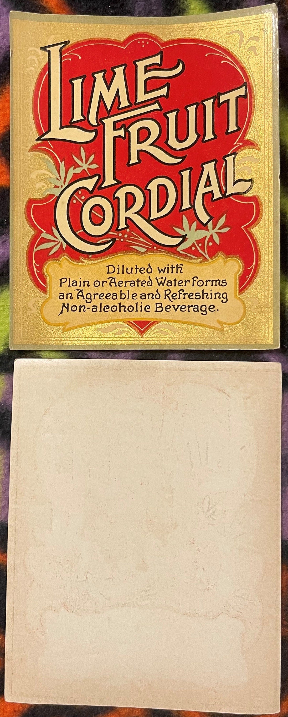 Vintage Lime Fruit Cordial label with red and gold Art Nouveau design, shown front and back on colorful fabric background.