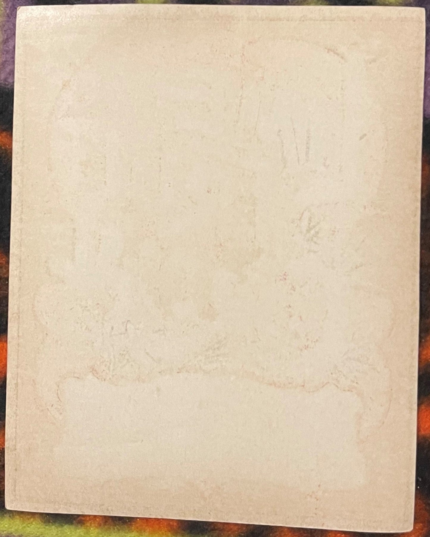 Cream-colored antique label with faint embossed or printed text, shown full-page against a colorful patterned background for 