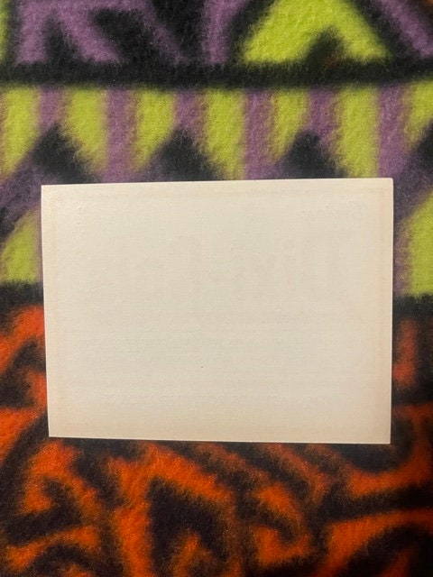 Blank cream-colored card displayed on colorful patterned fabric with purple, yellow, and orange geometric designs
