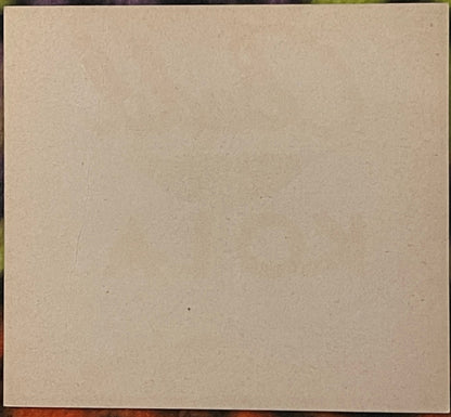 Blank cream-colored cardstock or label with visible texture and minor marks, displayed against dark border
