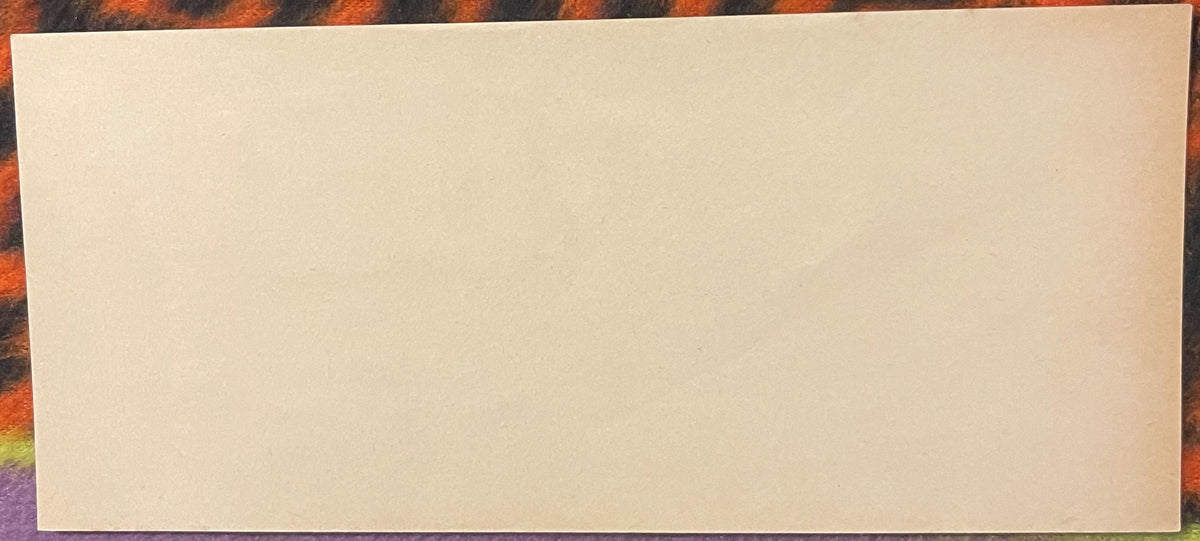 Blank cream-colored rectangular paper or label on colorful patterned fabric background