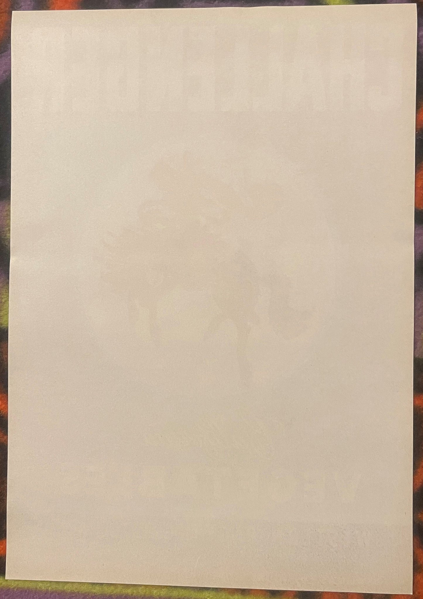 Blank cream-colored vintage crate label on colorful patterned background, front side visible
