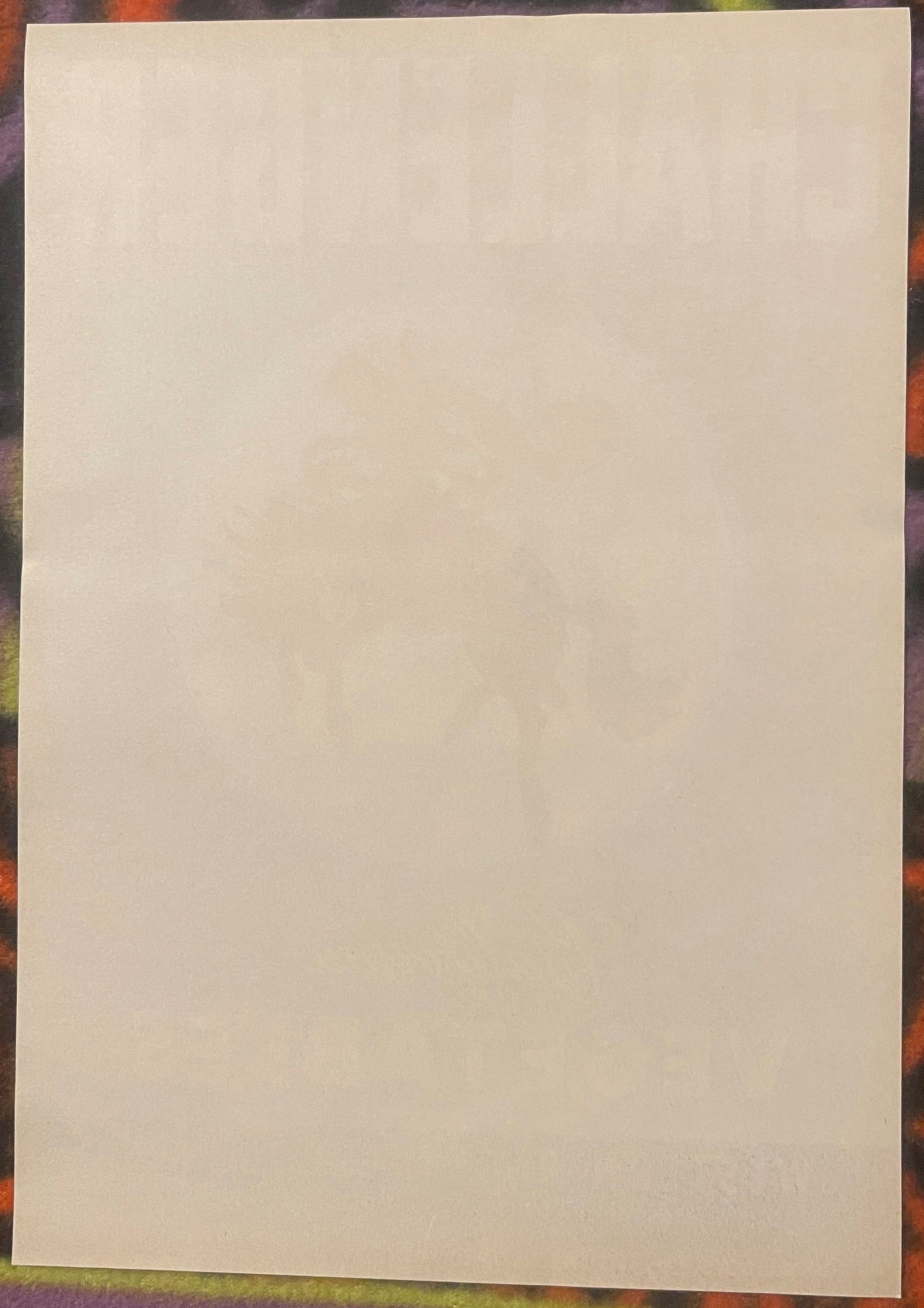 Blank cream-colored vintage crate label on colorful patterned background, front side visible