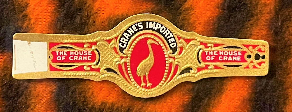 Ornate gold cigar band with red center oval featuring a crane, embossed text "Crane's Imported" and "The House of Crane" on s