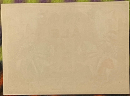 Blank cream-colored vintage beer label against colorful patterned background, showing paper texture and aging