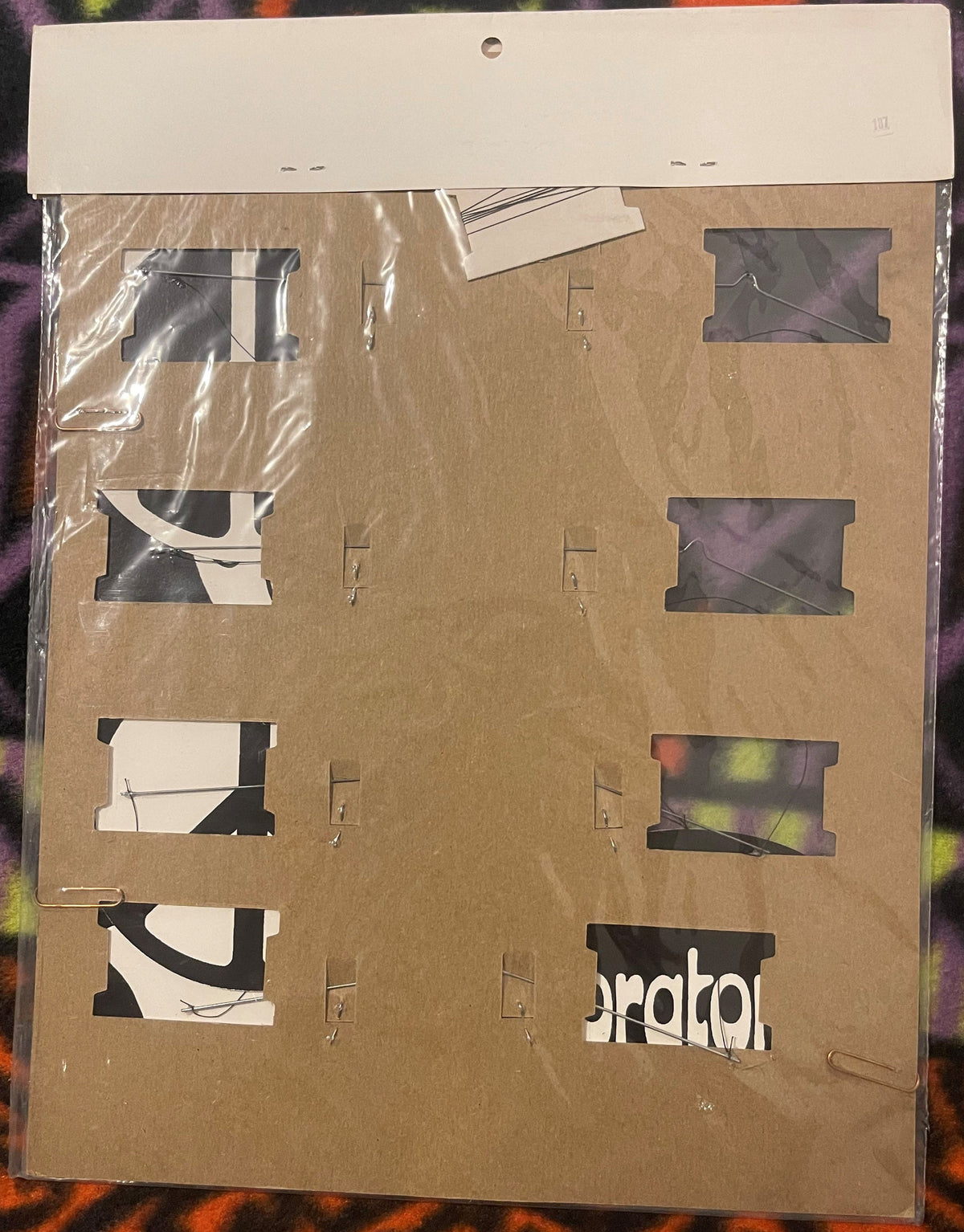 Cardboard product packaging with window cutouts displaying black and white graphics and colorful elements, sealed in plastic 