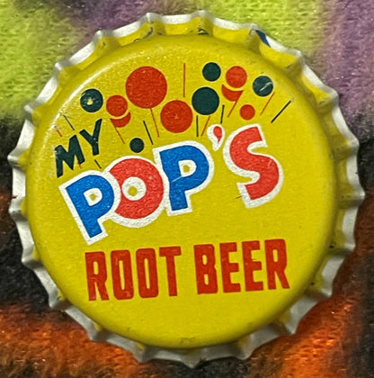 Vintage yellow bottle cap with "My Pop's Root Beer" text in blue and red lettering, decorated with red and dark blue circles,