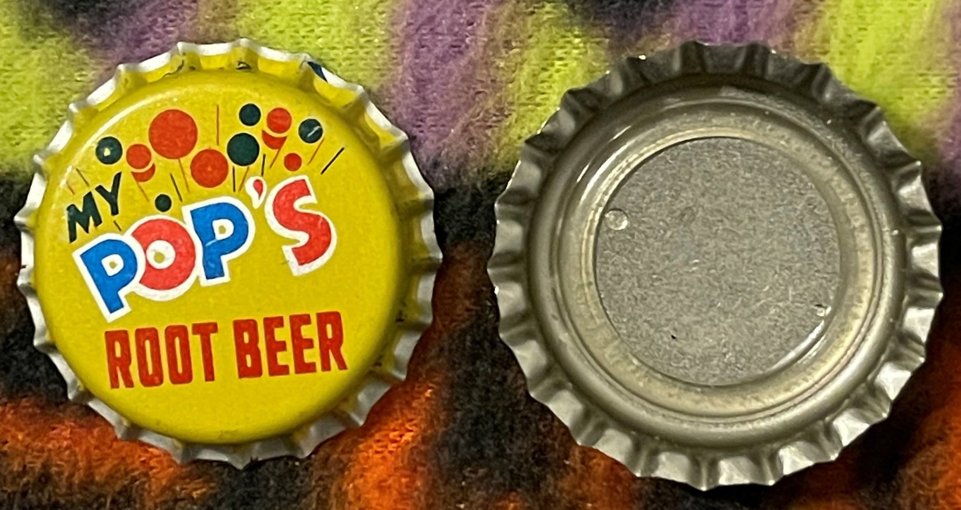 Vintage My Pop's Root Beer bottle cap showing yellow front with colorful dots and text, and metal reverse side, displayed on 