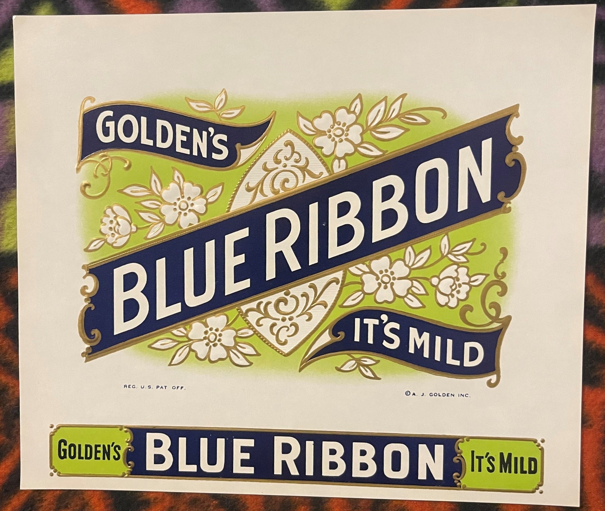 Vintage cigar label with ornate gold and cream botanical design on green and navy bands reading "Golden's Blue Ribbon It's Mi
