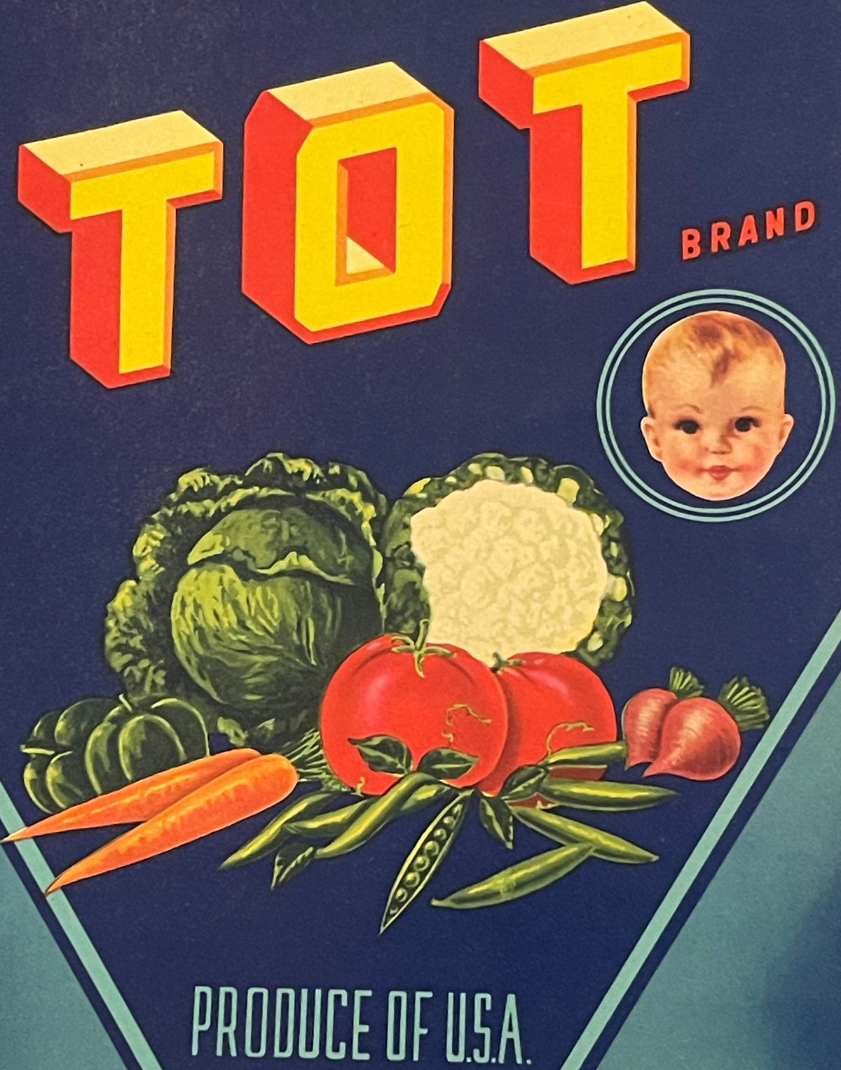 Vintage Tot Brand vegetable crate label with red and yellow 3D lettering, smiling baby portrait, and illustrated produce incl