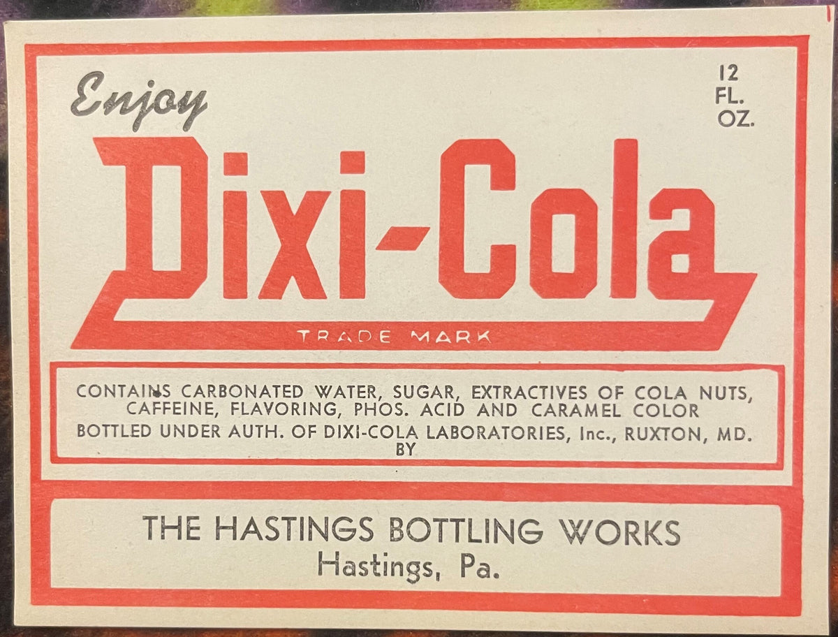 Vintage Dixi-Cola label from Hastings Bottling Works, Pennsylvania, 12 fl oz, with red and cream typography listing cola