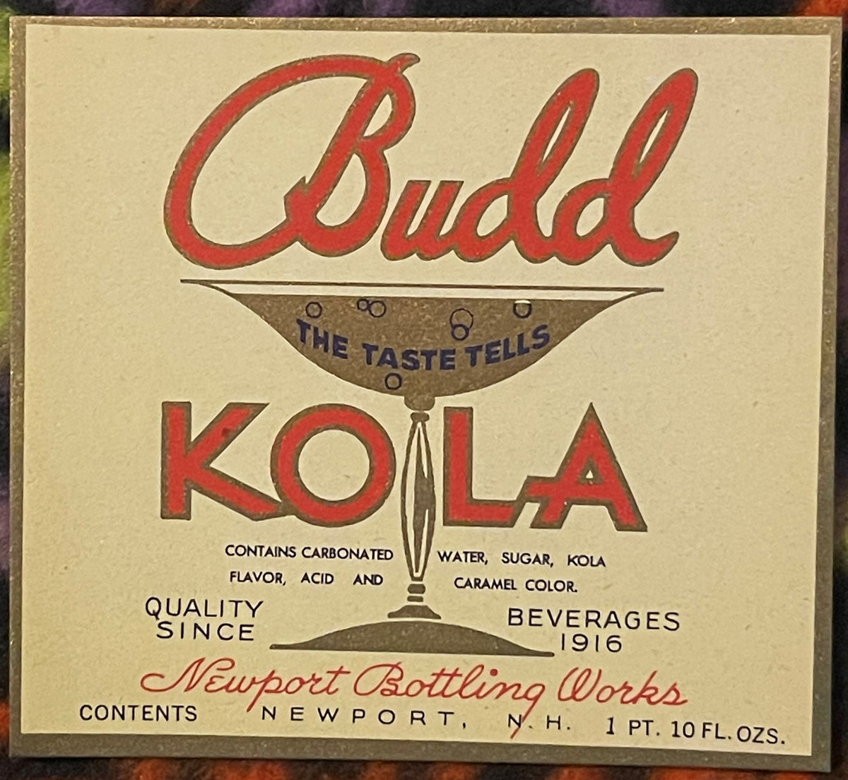 Vintage Budd Kola beverage label from Newport Bottling Works featuring red script text, brown illustration of a glass
