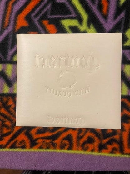 Cream-colored embossed cigar label with gold seal design on colorful patterned fabric background