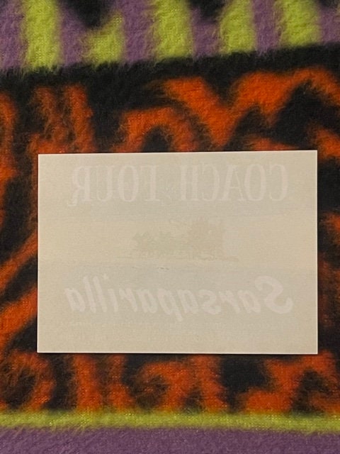 Blank cream-colored card centered on vintage orange and black patterned fabric with yellow-green striped border
