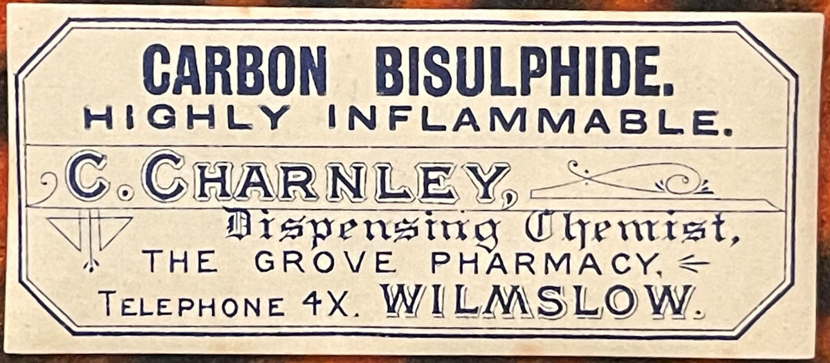 Vintage pharmaceutical label for carbon bisulphide in cream and dark blue text, printed by C. Charnley Dispensing Chemist of 