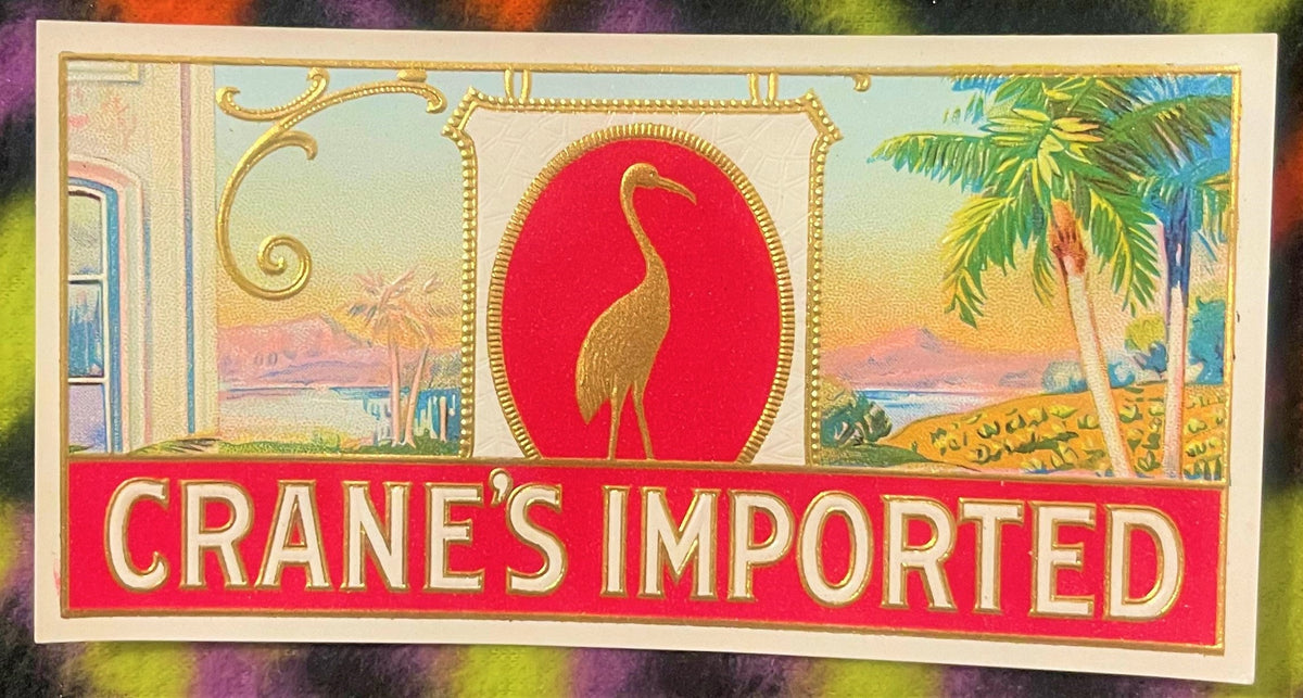 Vintage "Crane's Imported" cigar label featuring gold crane bird on red oval against tropical landscape with palm trees and w