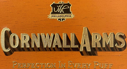 Close-up of the woodgrain Cornwall Arms label: Harold Levy's HL monogram shield over PHILADELPHIA and CORNWALL ARMS in embossed gold with a deep shadow.